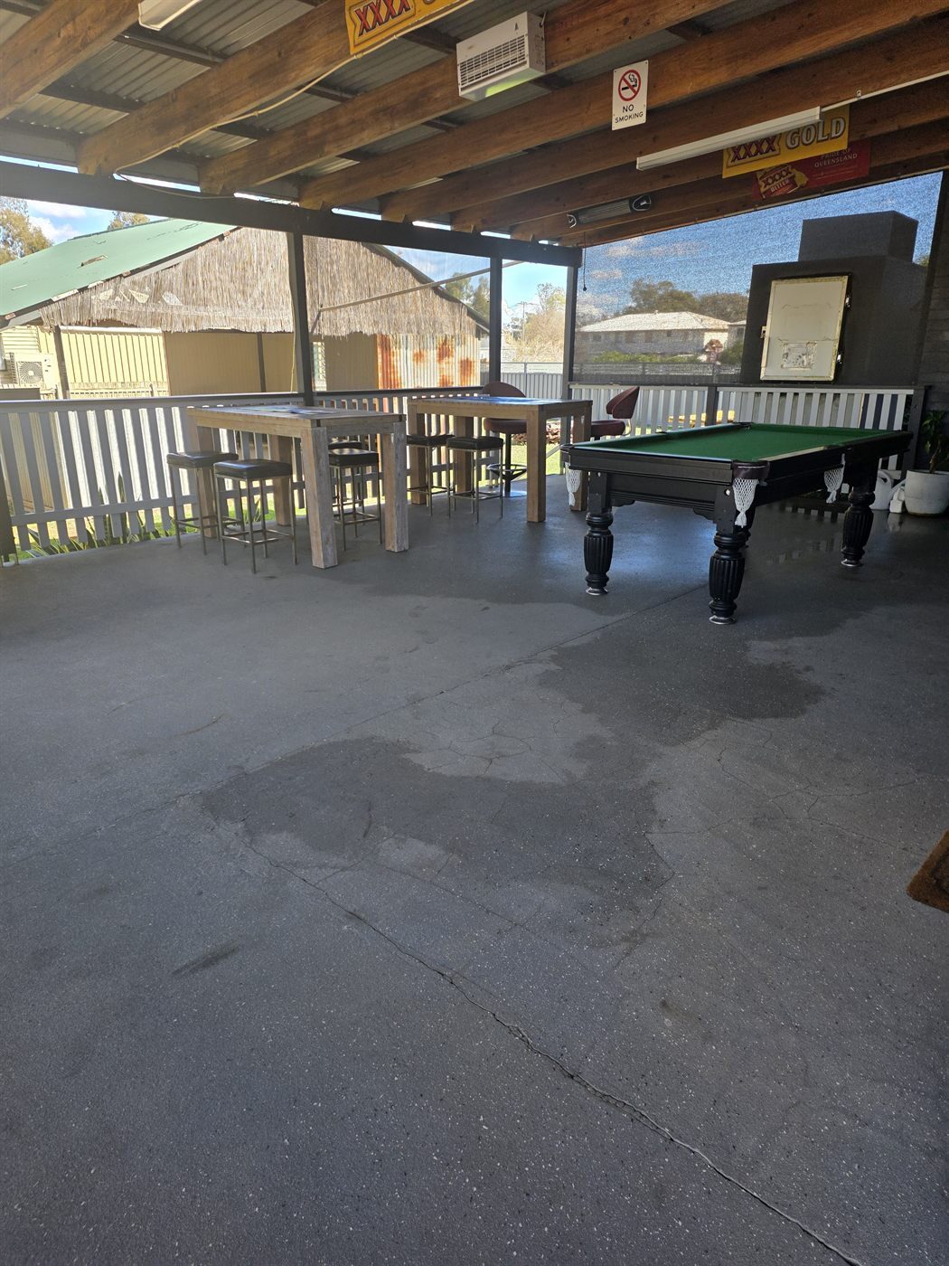 Covered outdoor area with a pool table and high bar tables